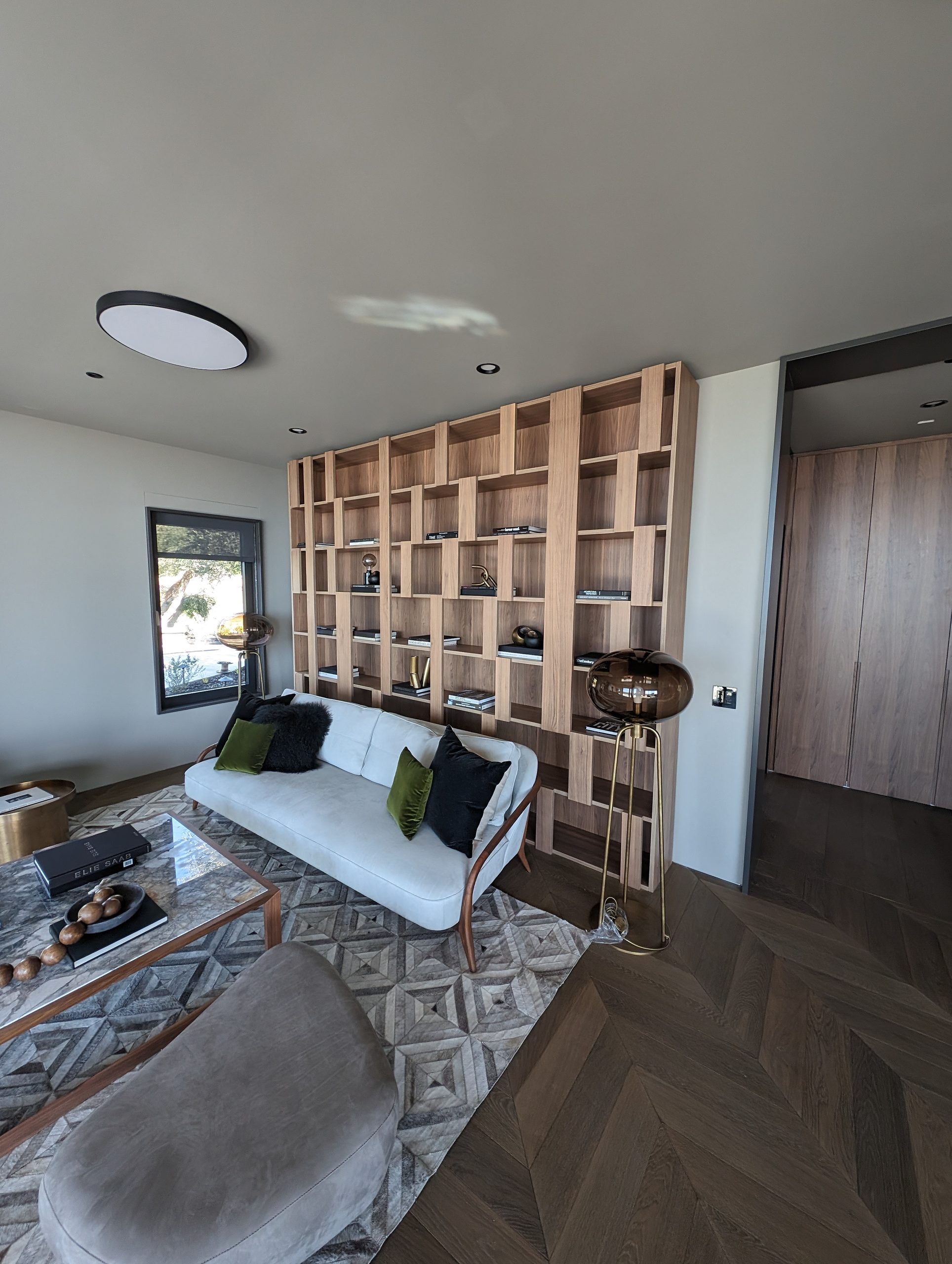 Custom oak grid shelving wall behind the living room seating, on herringbone floors