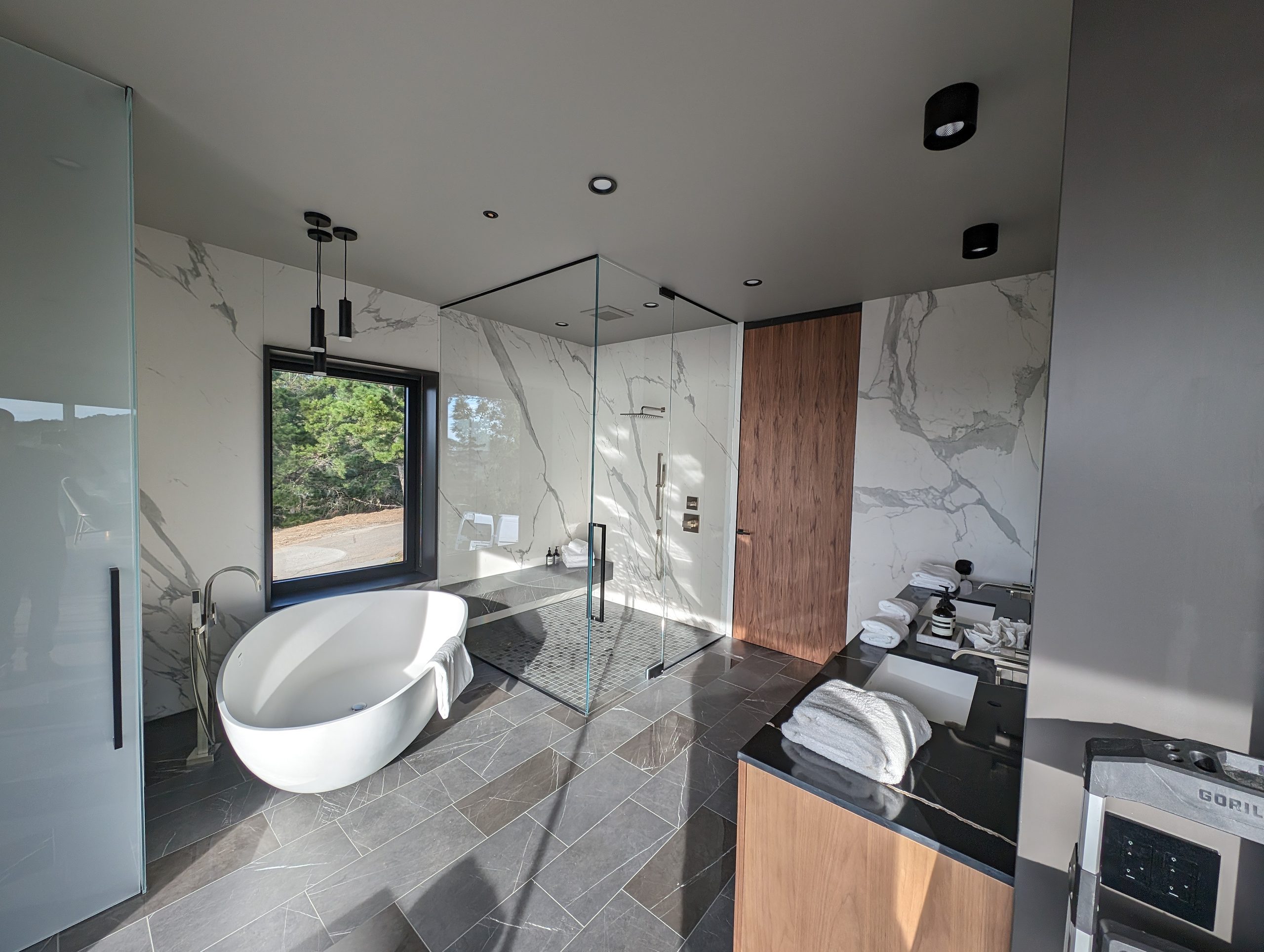 Freestanding tub set against book-matched marble, walnut door alongside