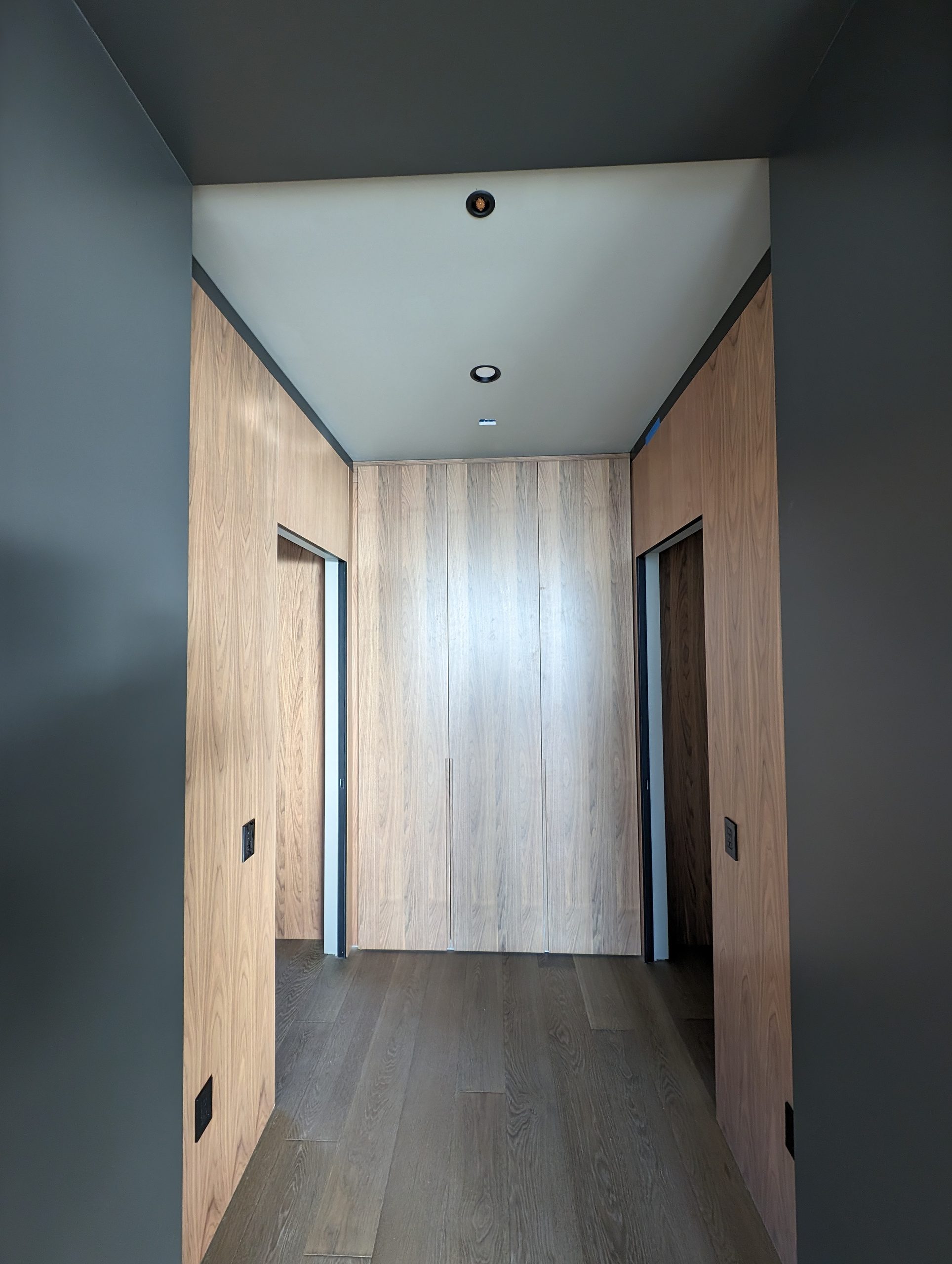 Paneled corridor with concealed flush doors reading as continuous wall