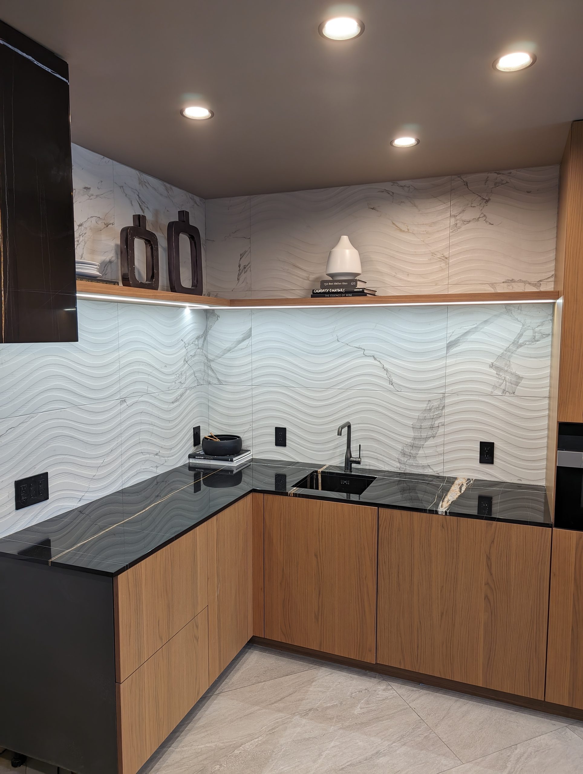 Prep kitchen corner with dark stone worktop and lit open shelf