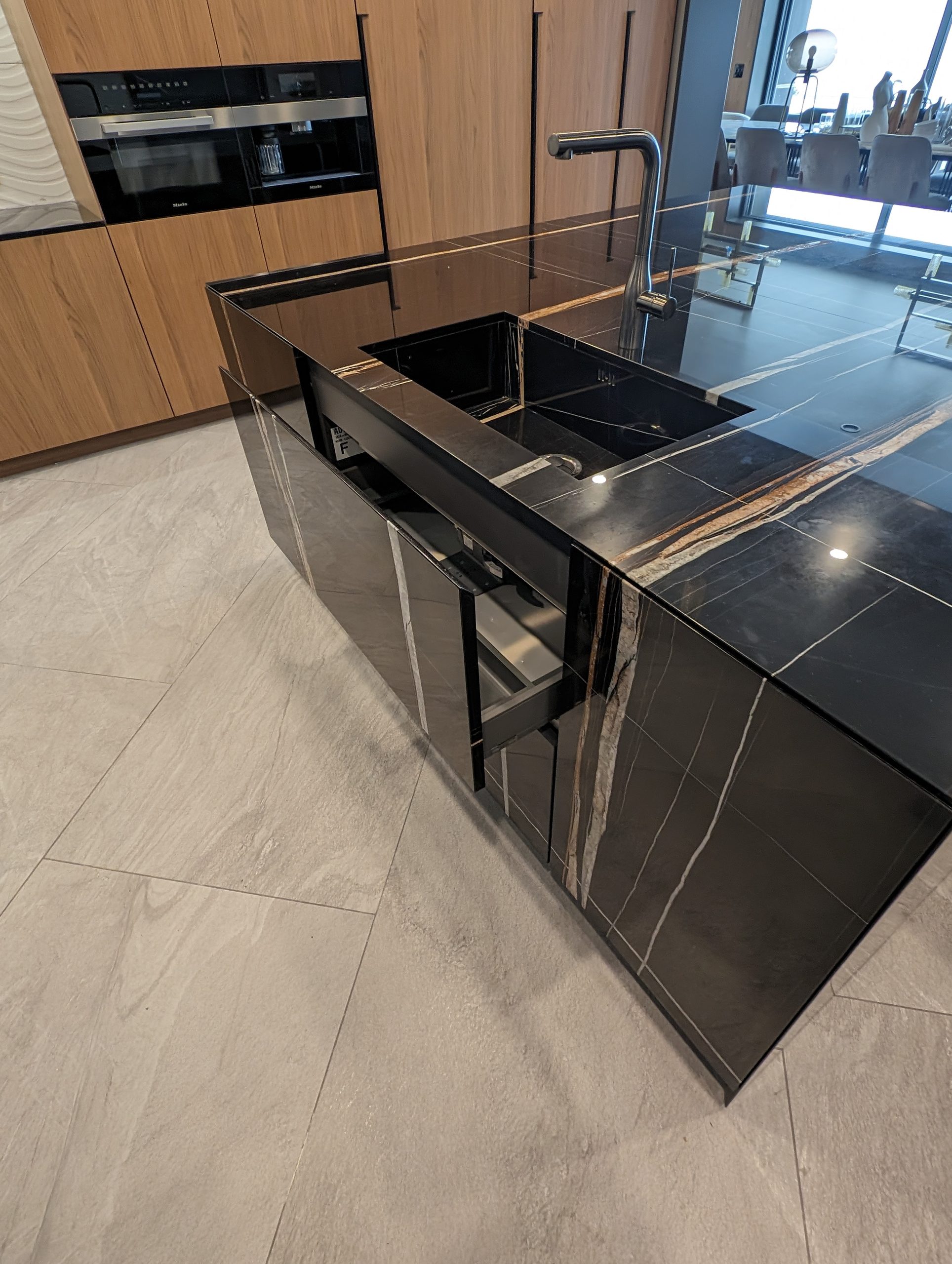 Black marble island with mitred waterfall ends, tall ovens behind