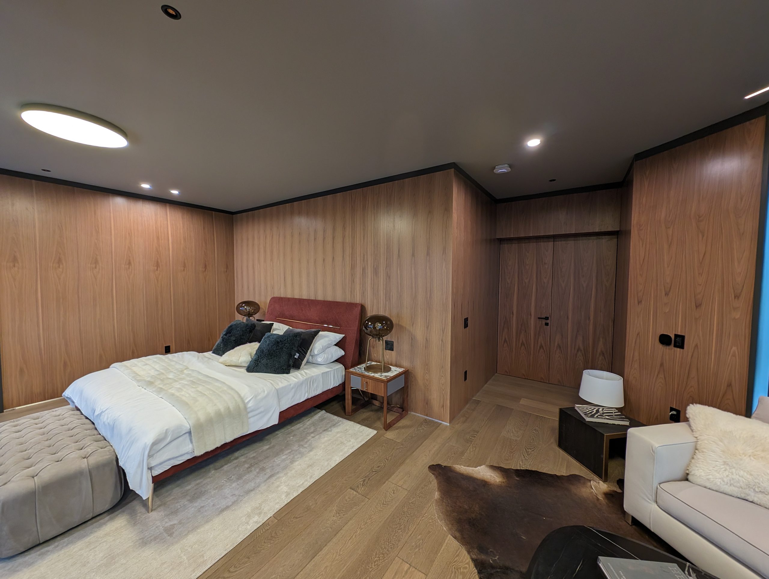 Bedroom lined in walnut paneling with concealed door leaves