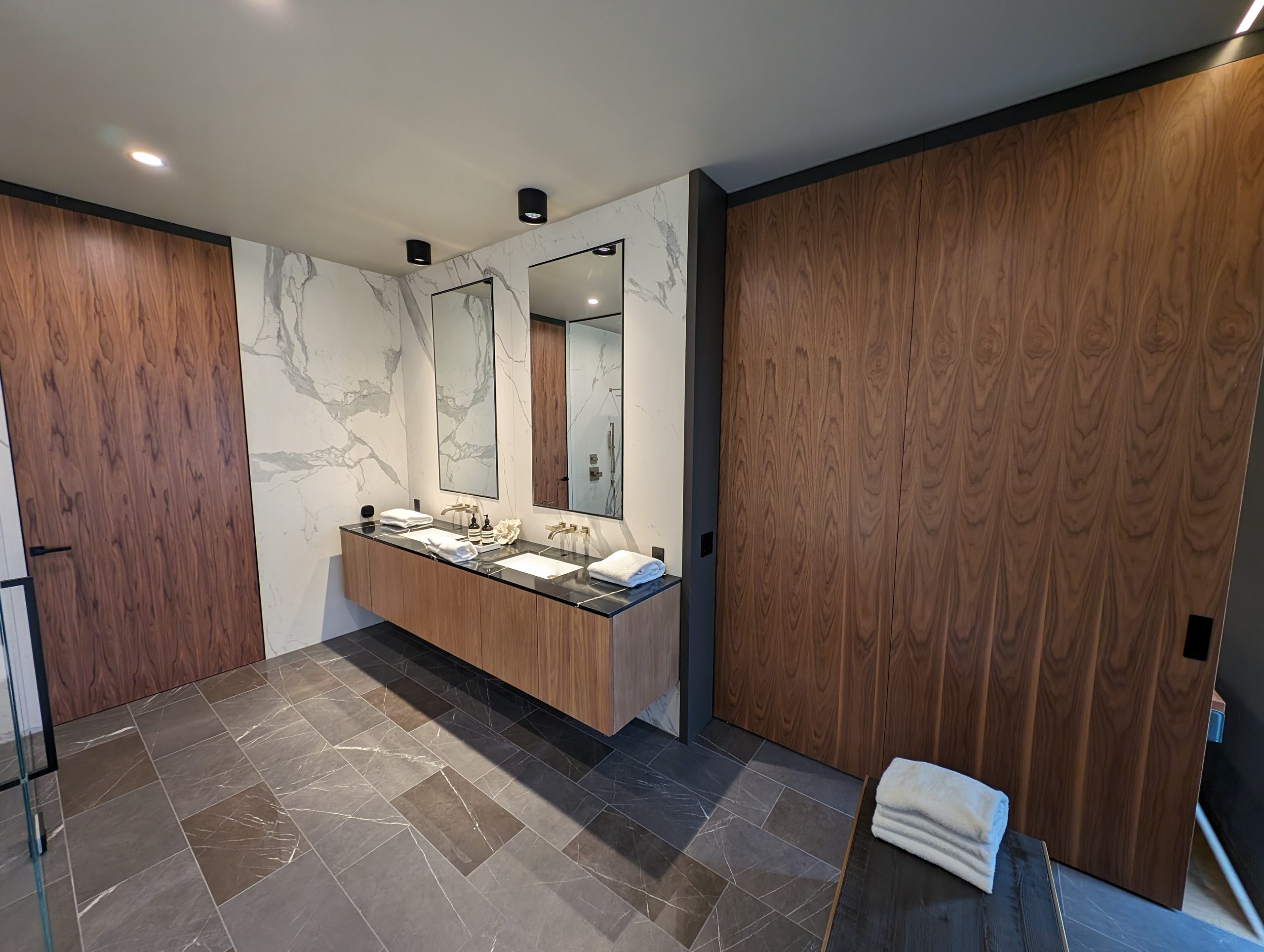 Full-height walnut door closing the bath off from the bedroom