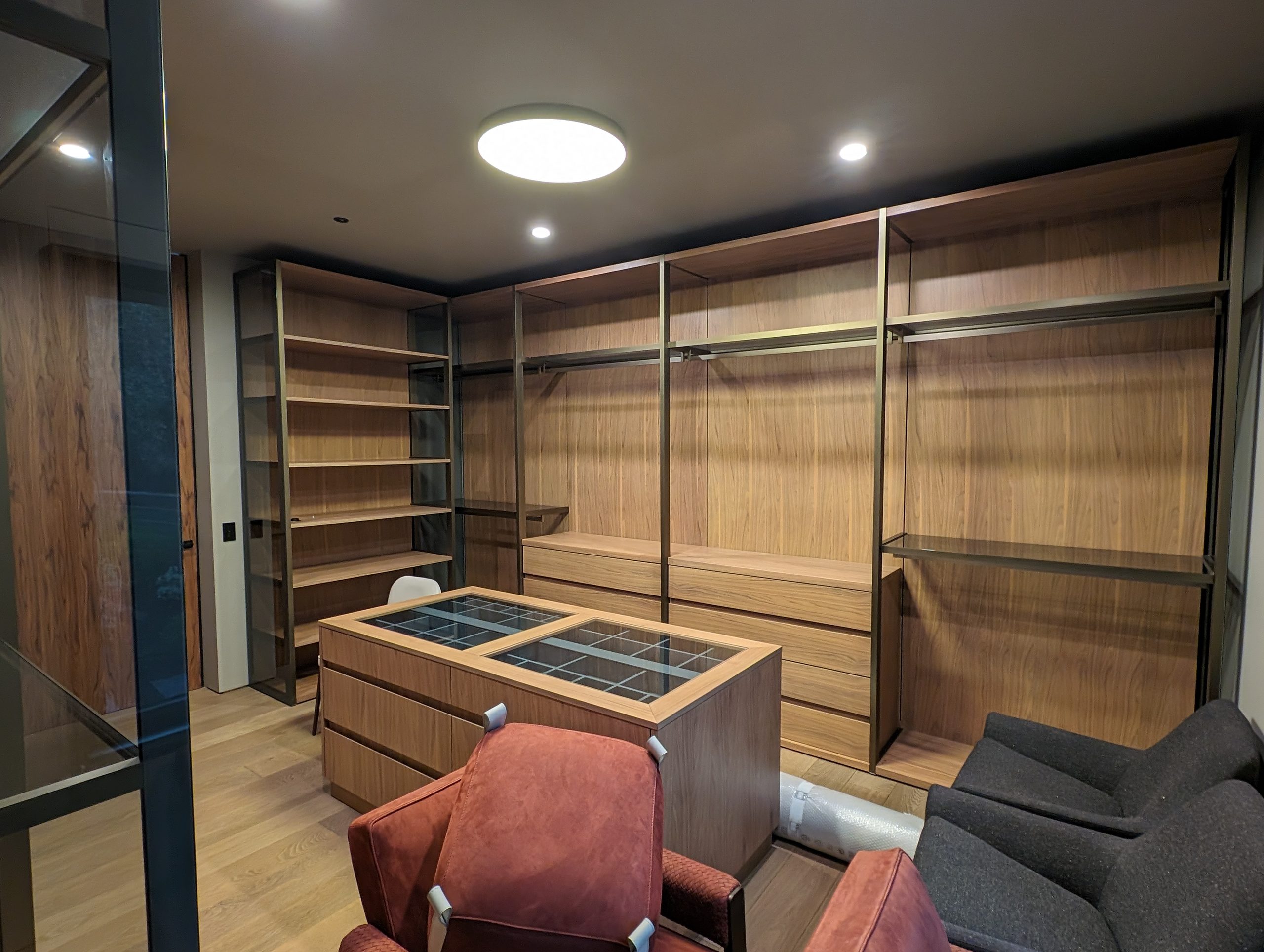 Dressing room with glass-front wardrobes, slim aluminium open system, and a glass-top island