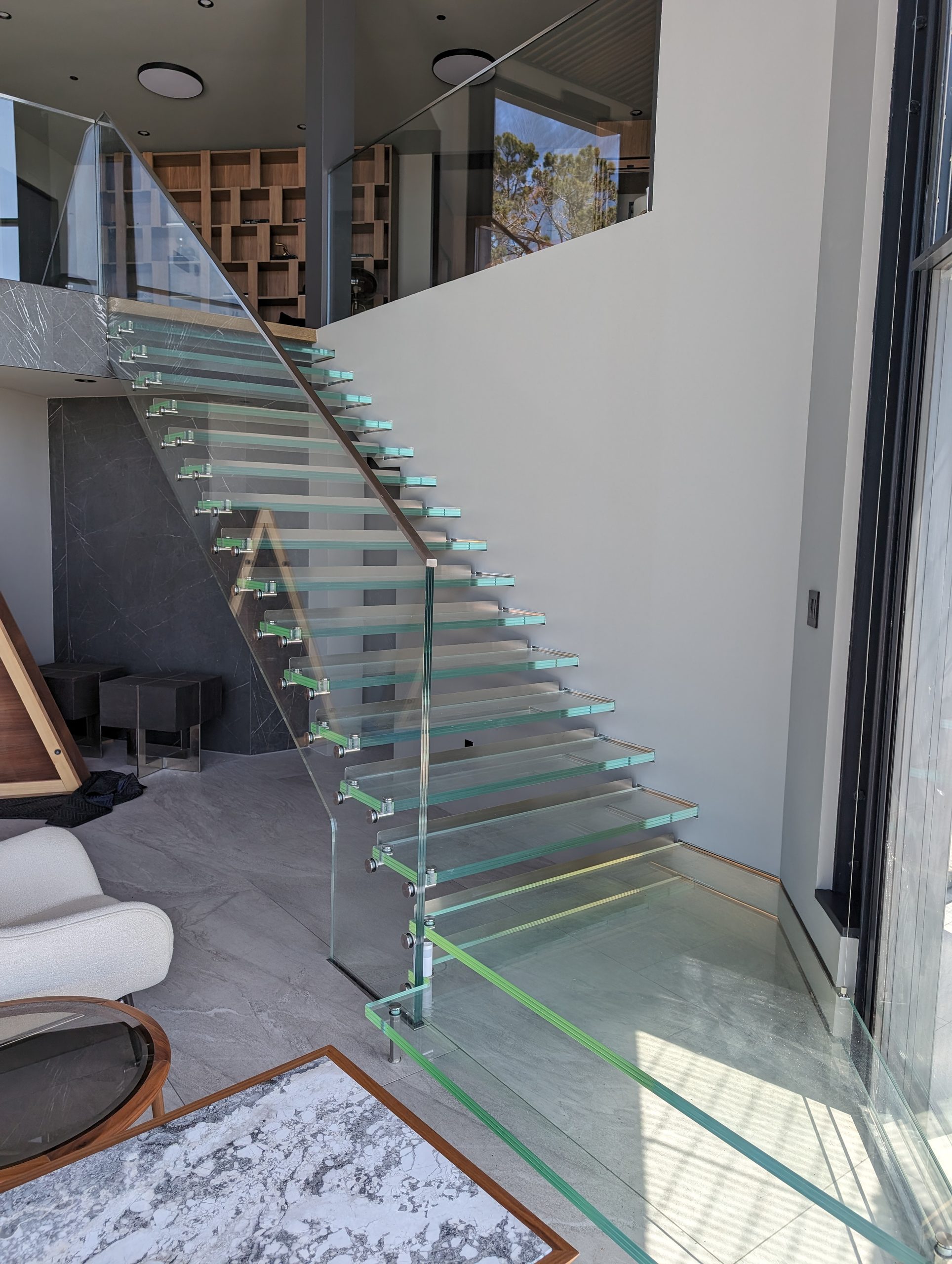 Glass-tread stair rising past the double-height living volume