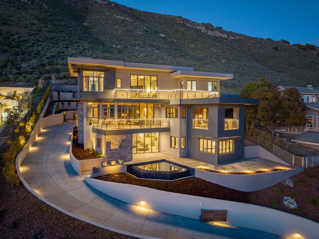 Street elevation at dusk — three storeys of stone, glass, and stucco on the curved drive