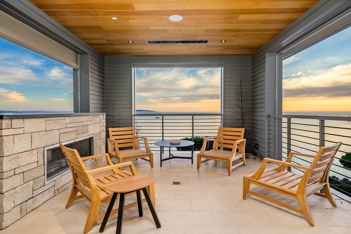 Covered deck with stone fireplace and teak lounge chairs