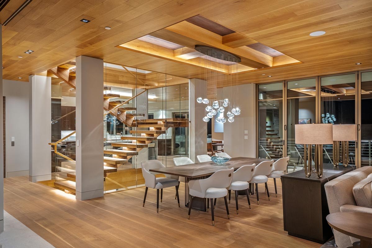 Dining room under the coffered oak ceiling, the floating stair behind glass