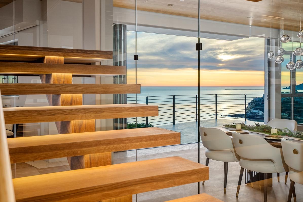 The stair against the sunset, treads cantilevered past the glass