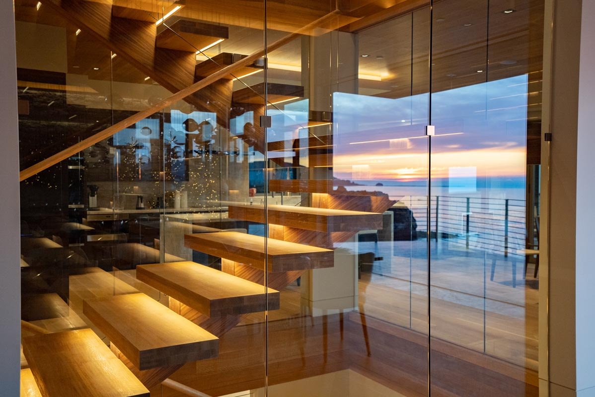 The stair shaft in smoked glass, sunset reflected through the treads