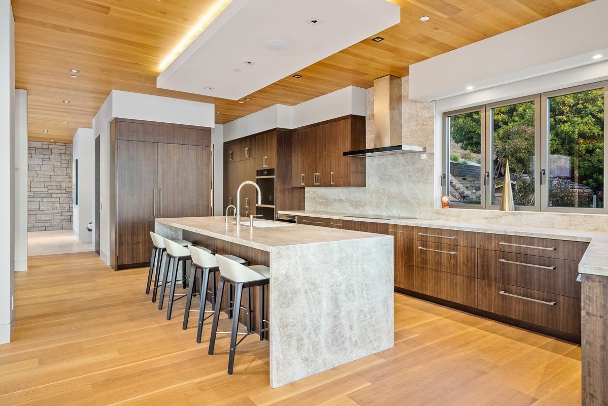 Kitchen under the oak ceiling — tall walnut appliance wall and island seating