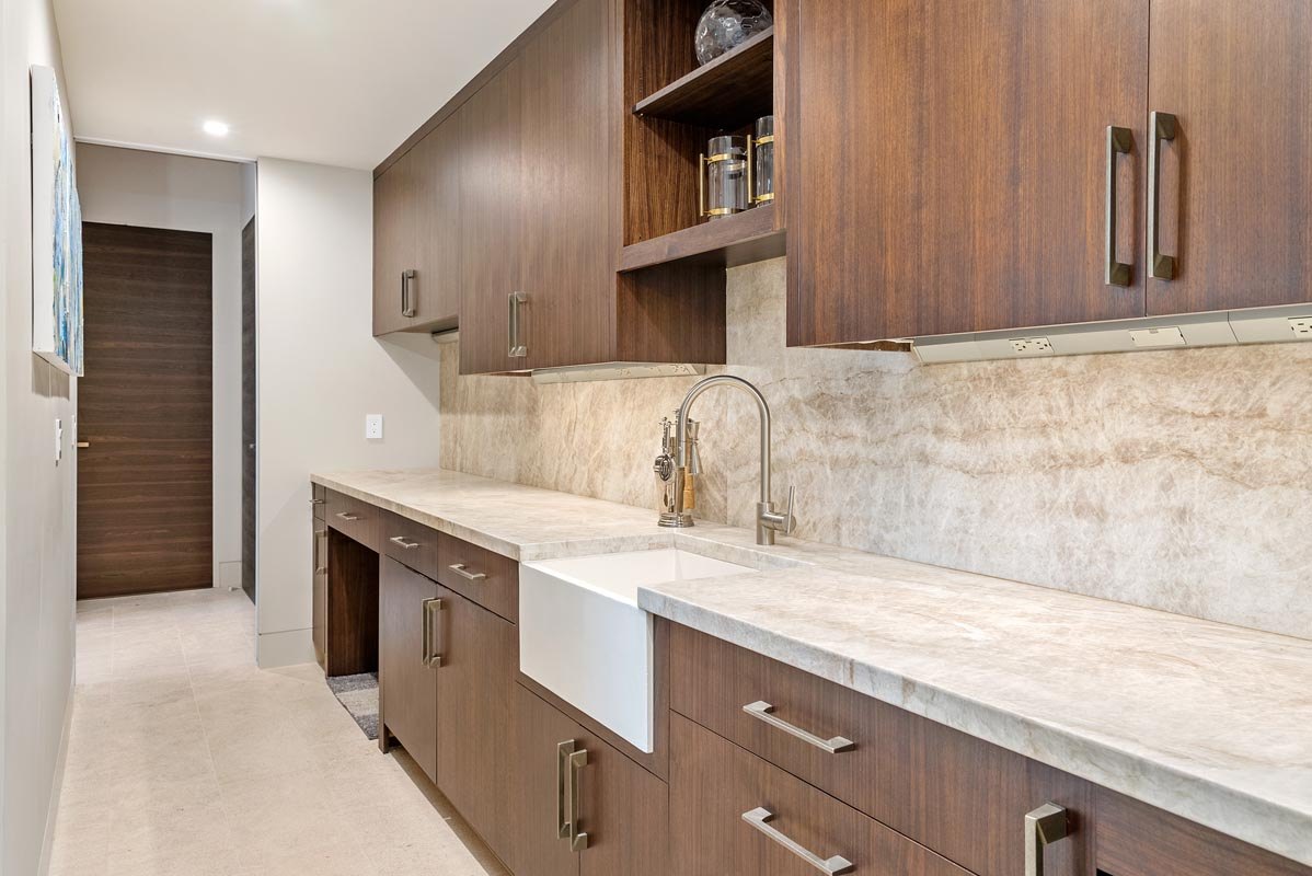 The scullery run — walnut cabinetry, stone splash, and an apron-front farmhouse sink
