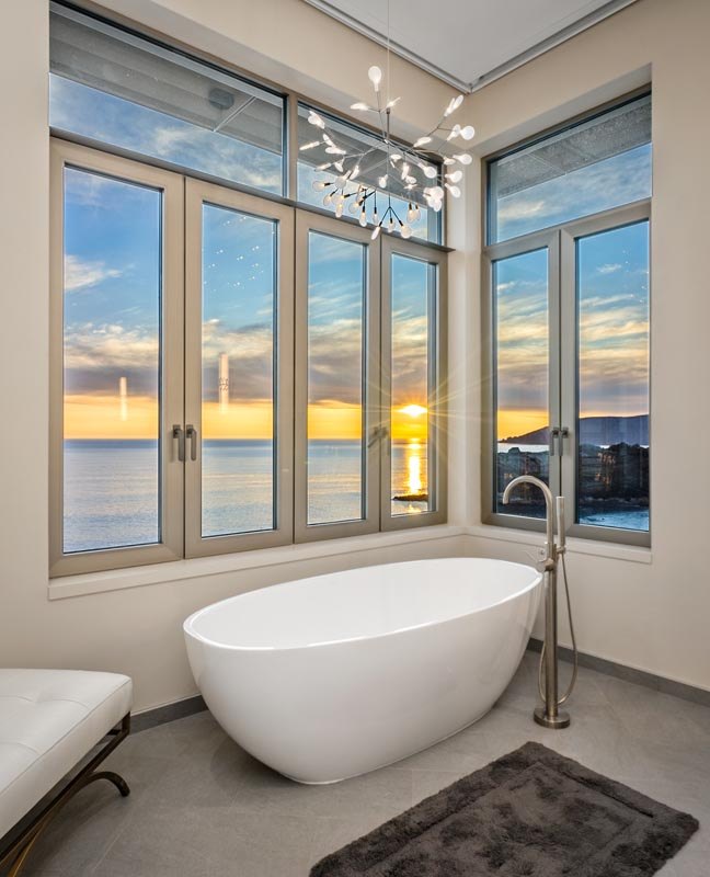 Freestanding tub in the corner window, sunset over the water