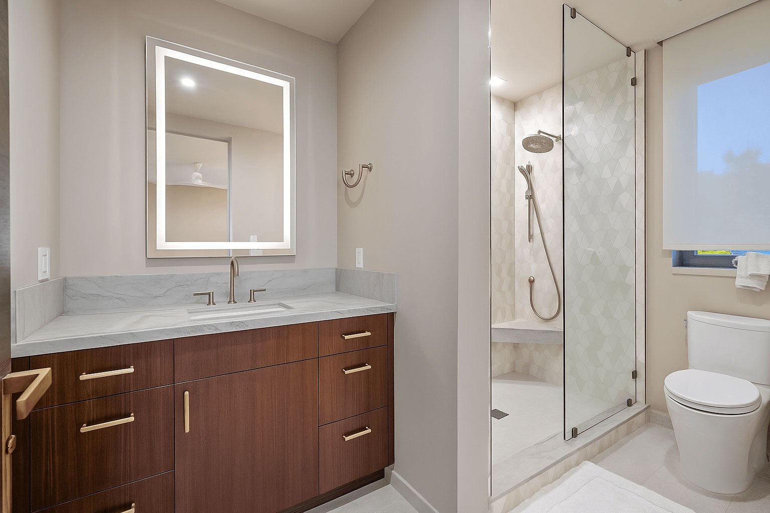 Guest bath — walnut vanity, stone top, and frameless glass shower