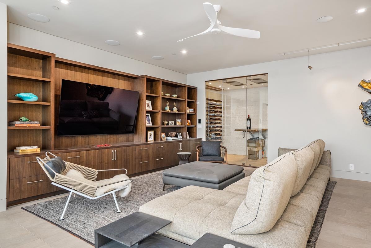 Family room media wall in walnut, open shelving and window to the cellar